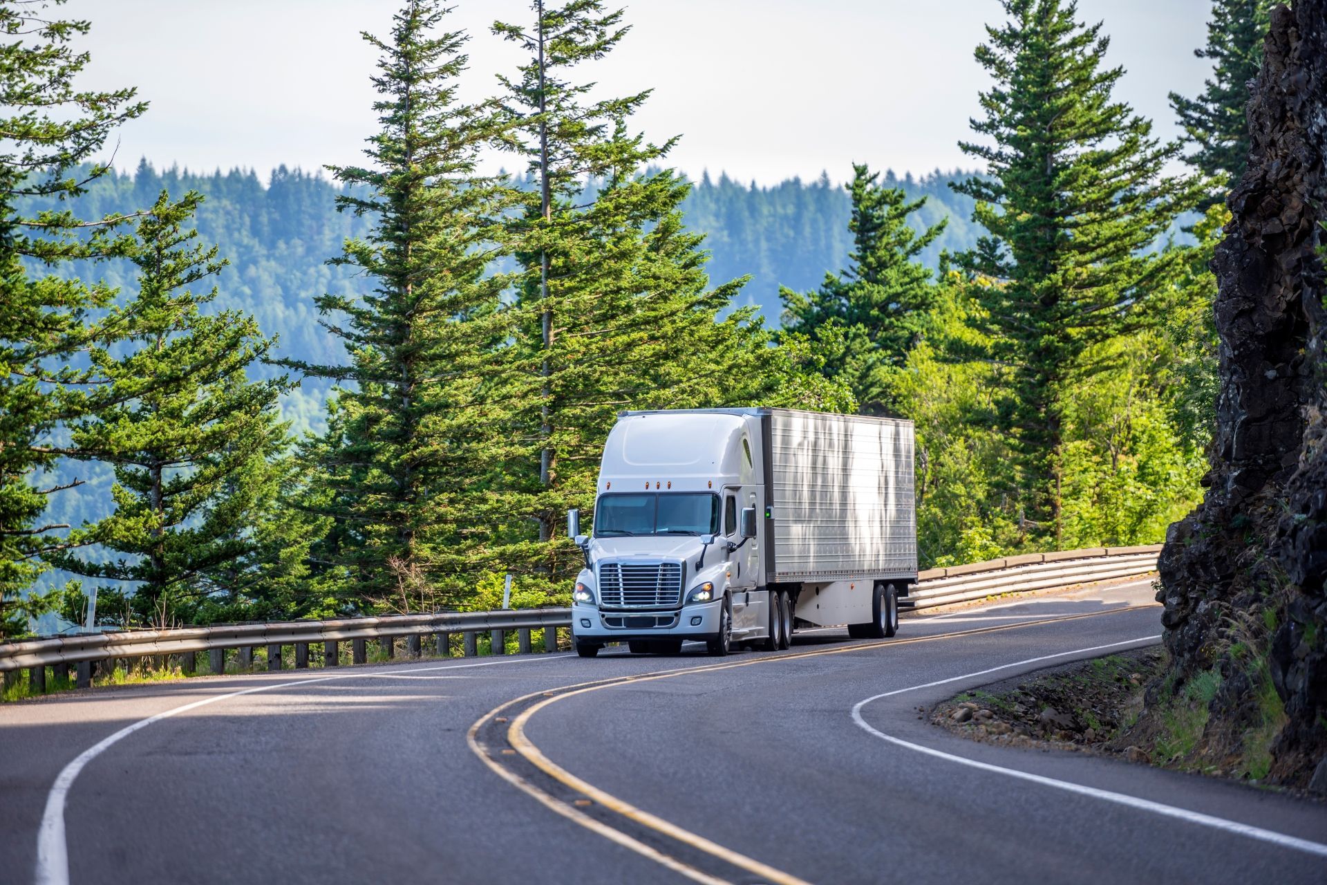 A white semi truck is parked in front of a wooden building.