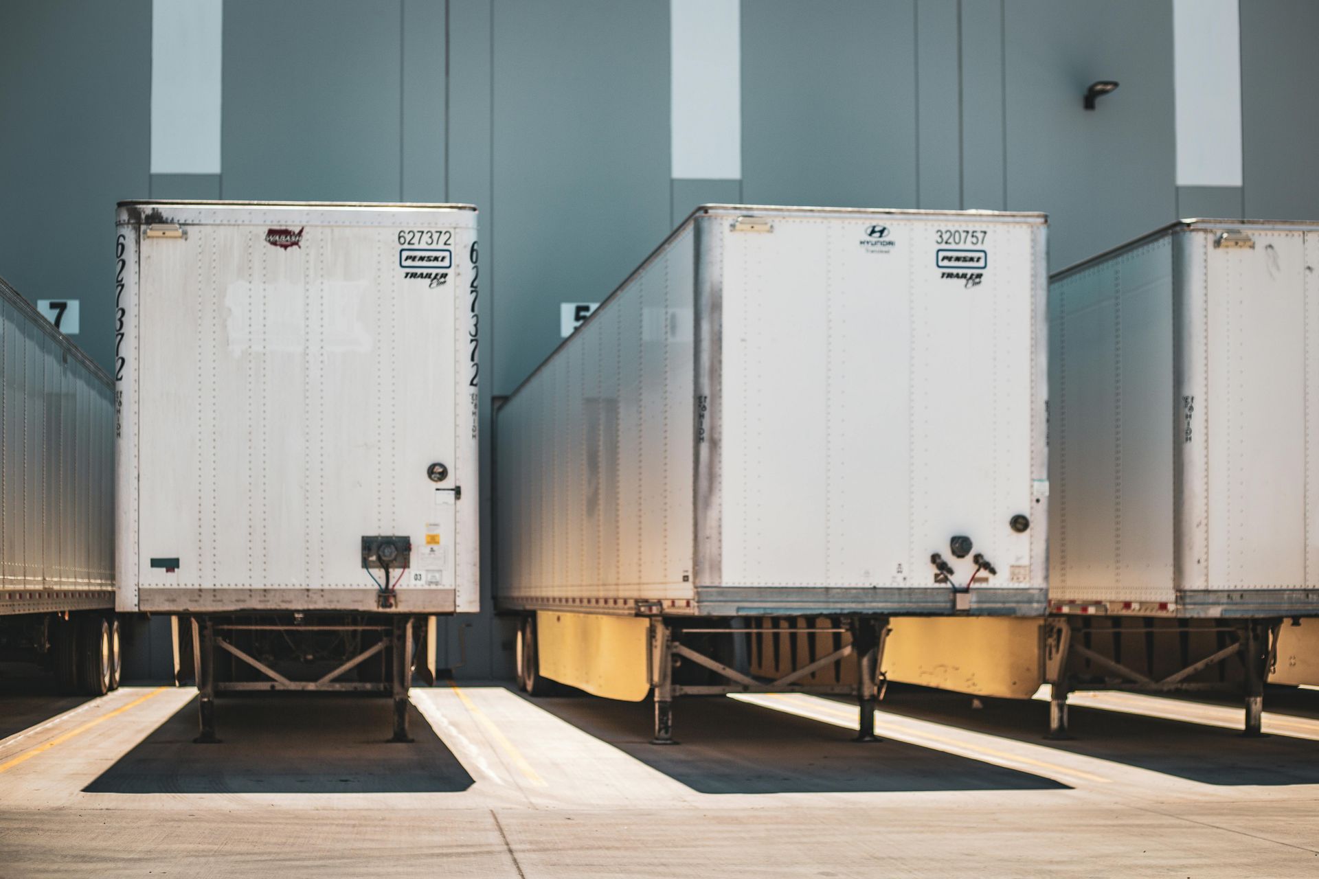 A row of white semi trucks parked in front of a building.