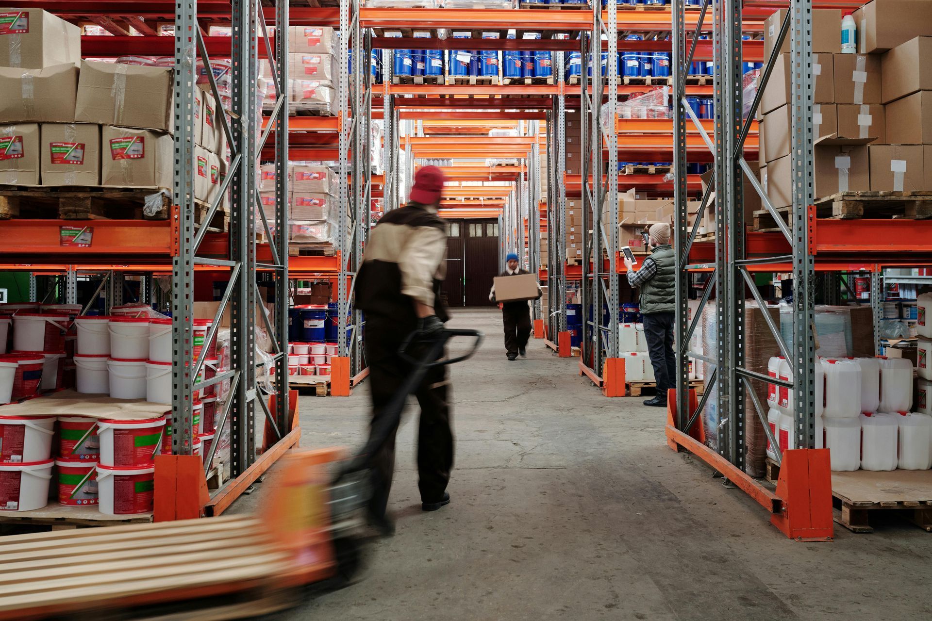 A man is pushing a pallet in a warehouse.