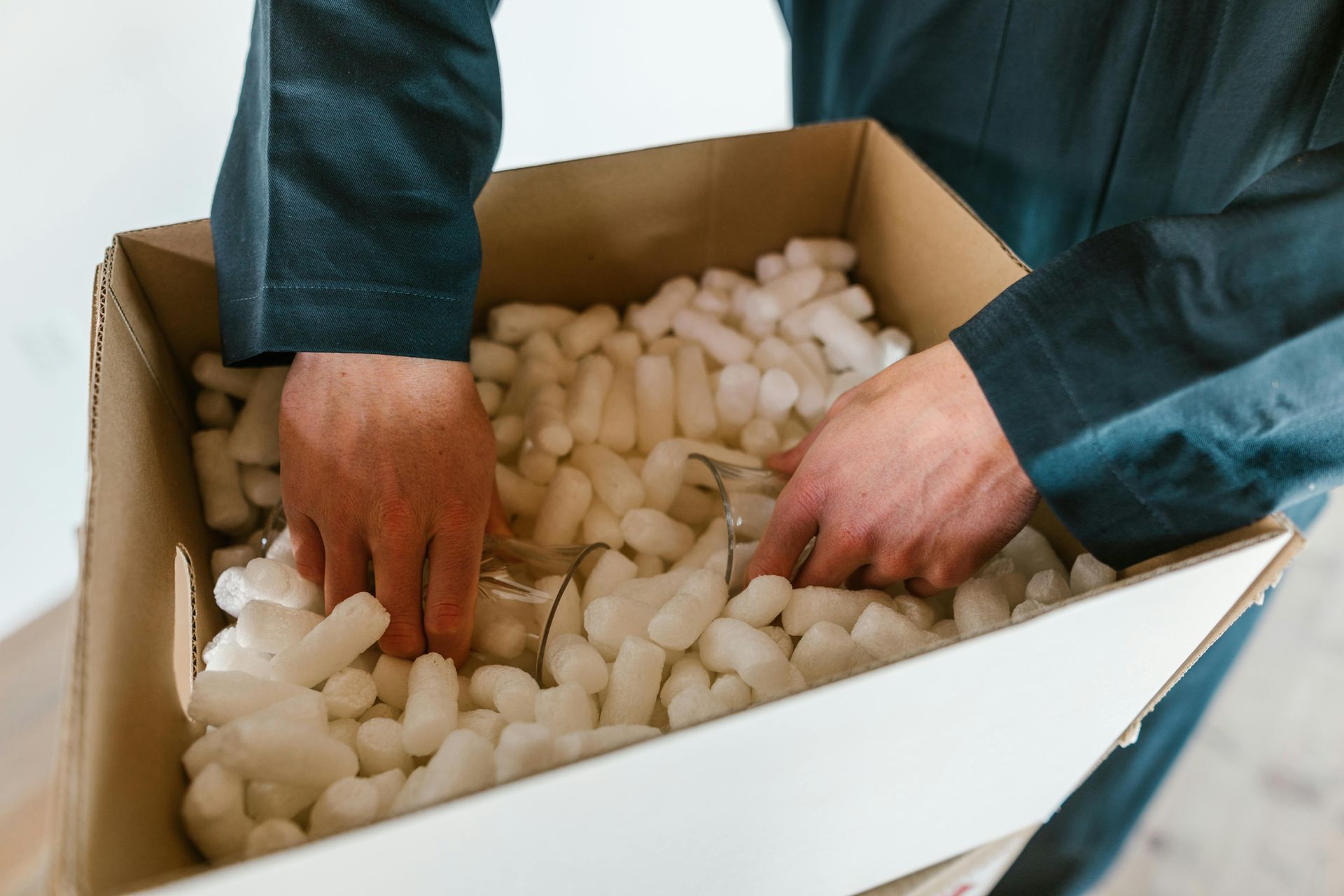 A man is holding a cardboard box filled with styrofoam peanuts.