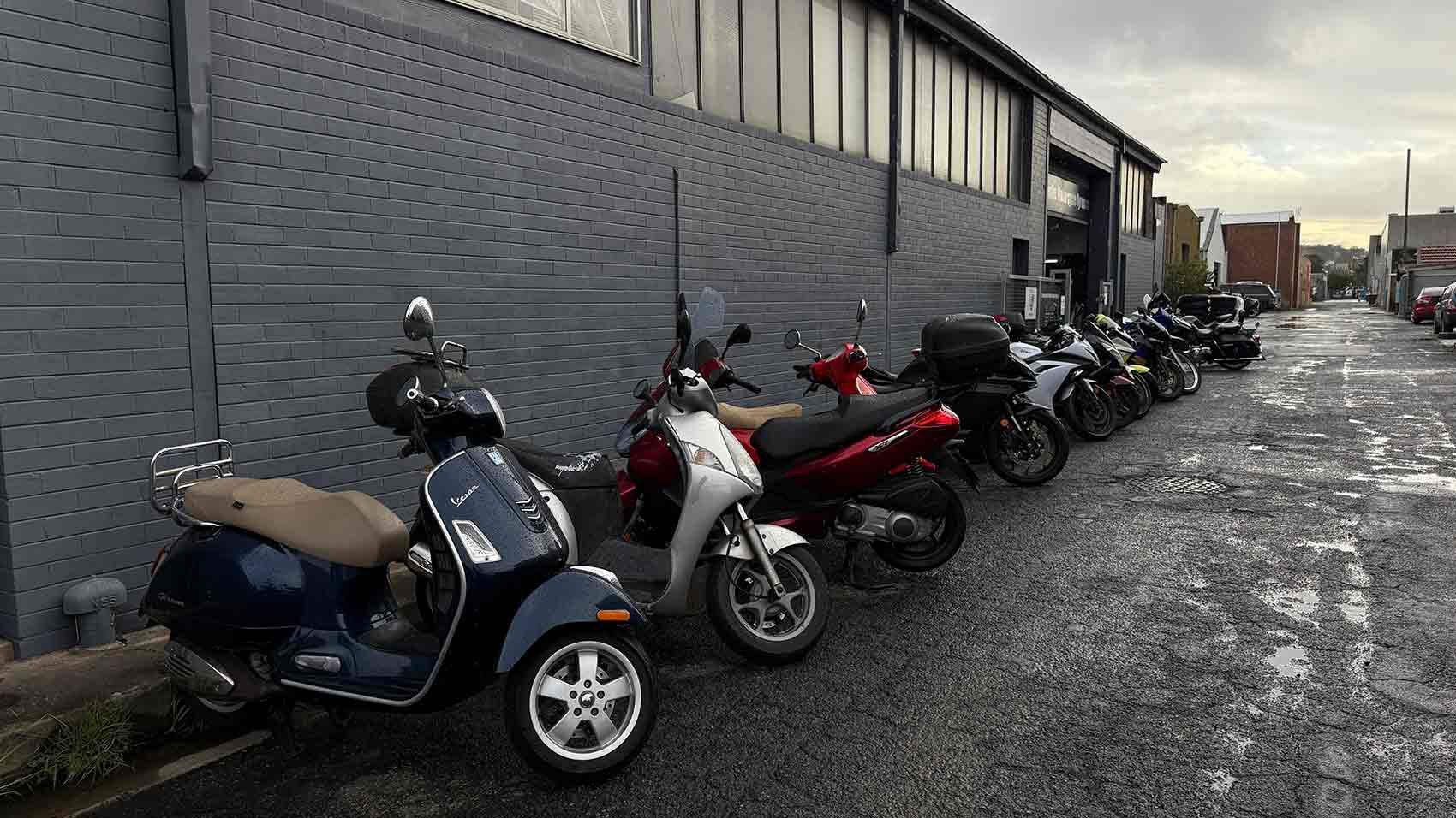 Scooters Parked Along a Gray Brick Building on a Cobblestone Street — Newcastle Motorcycle Tyres in Broadmeadow, NSW