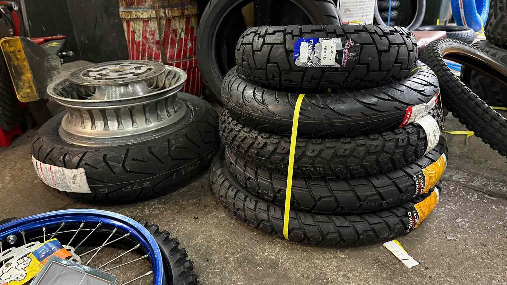 Pile of Motorcycle Tires Secured With a Yellow Cord, With a Wheel — Newcastle Motorcycle Tyres in Broadmeadow, NSW