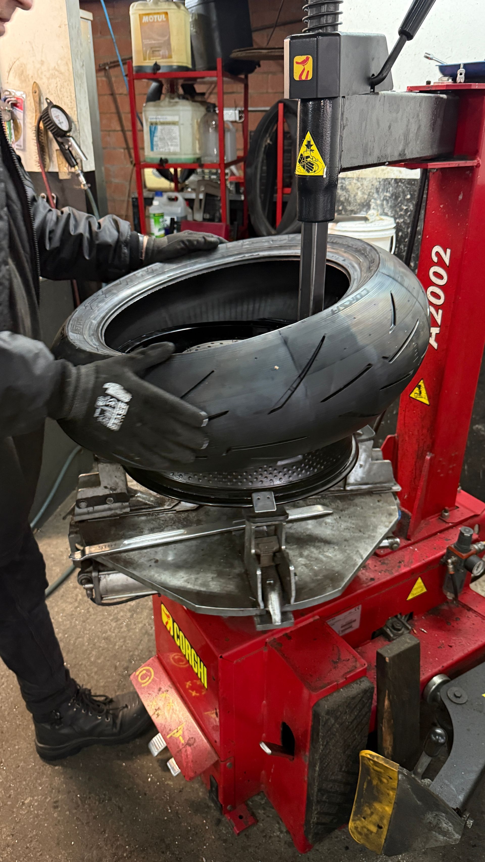 A man is putting a tyre on a rim metal frame while wearing black gloves — Newcastle Motorcycle Tyres in Broadmeadow, NSW