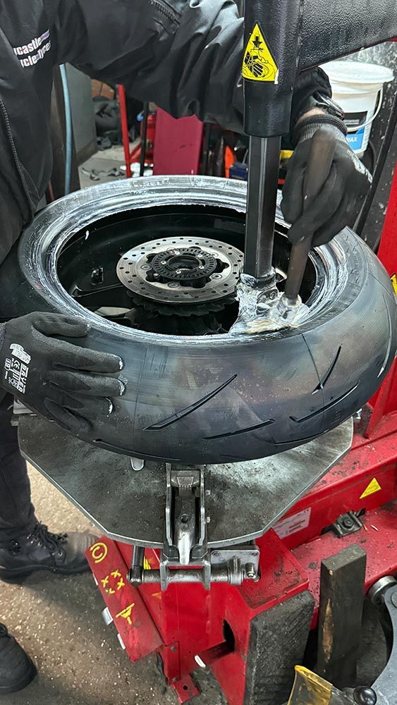 A Mechanic Changing a Motorcycle Tire on a Tire Machine Indoors — Newcastle Motorcycle Tyres in Broadmeadow, NSW