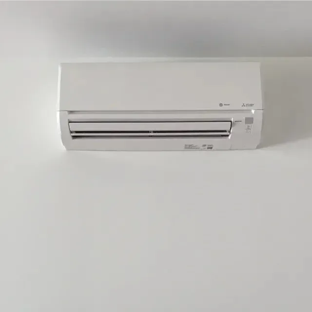 A white air conditioner is hanging on a white wall.