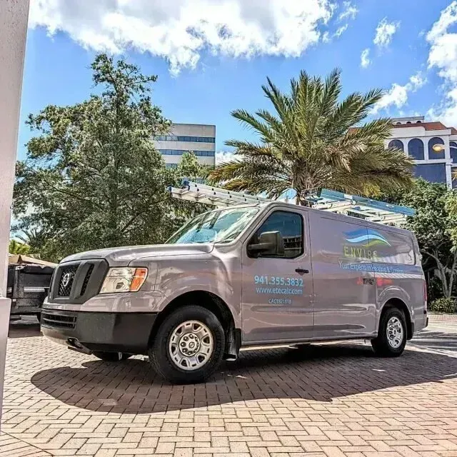 Hvac-Contractor-Bradenton-Grey service van with company logo parked on brick near a building. Palm tree in the background.