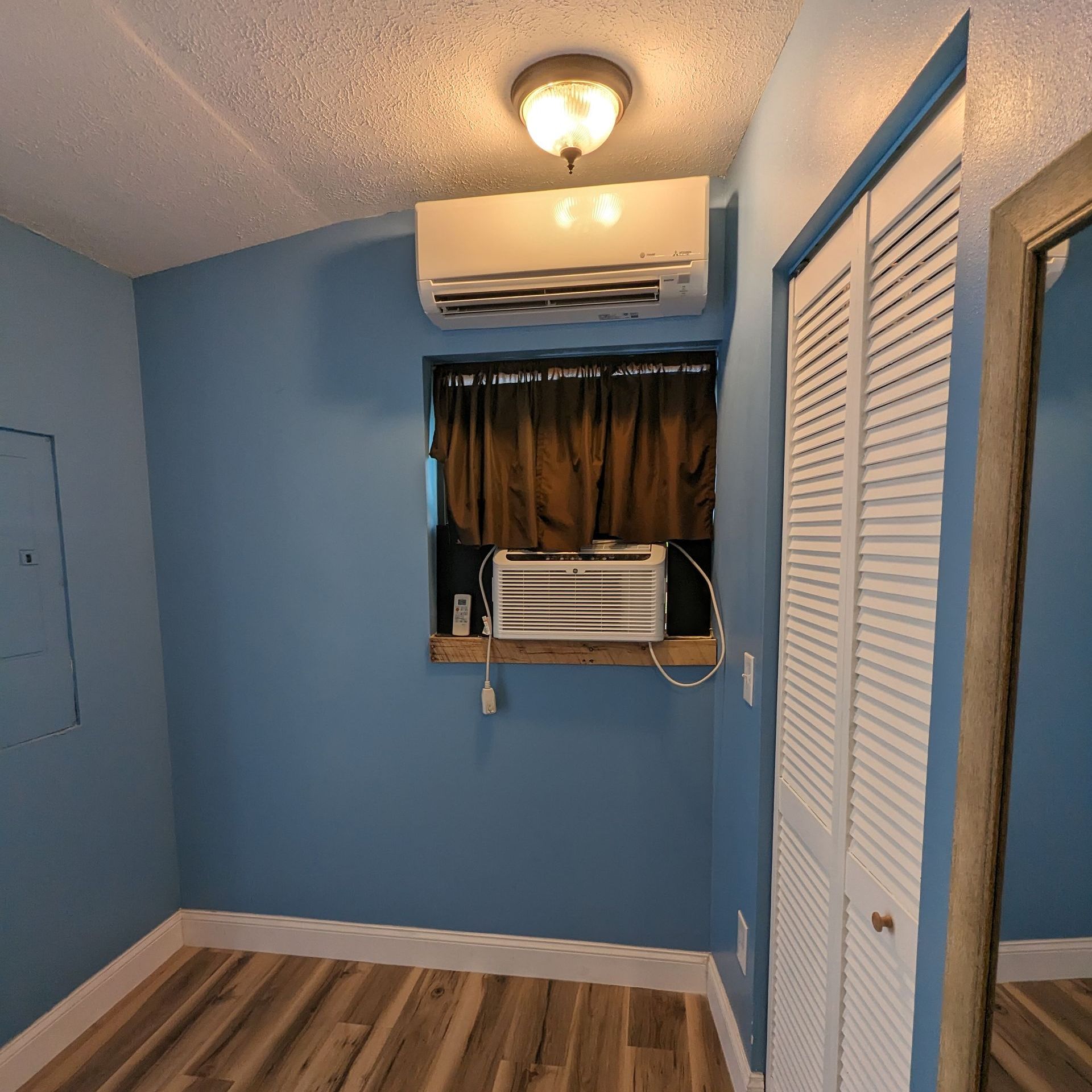 a room with blue walls and a window with an air conditioner