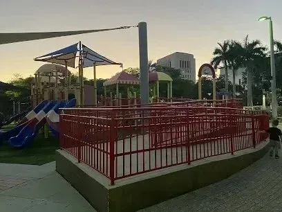 Hvac-Contractor-Bradenton-A child is standing in front of a playground with a red fence.