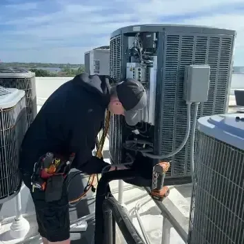 Hvac-Contractor-Bradenton-A man is working on an air conditioner on a roof.