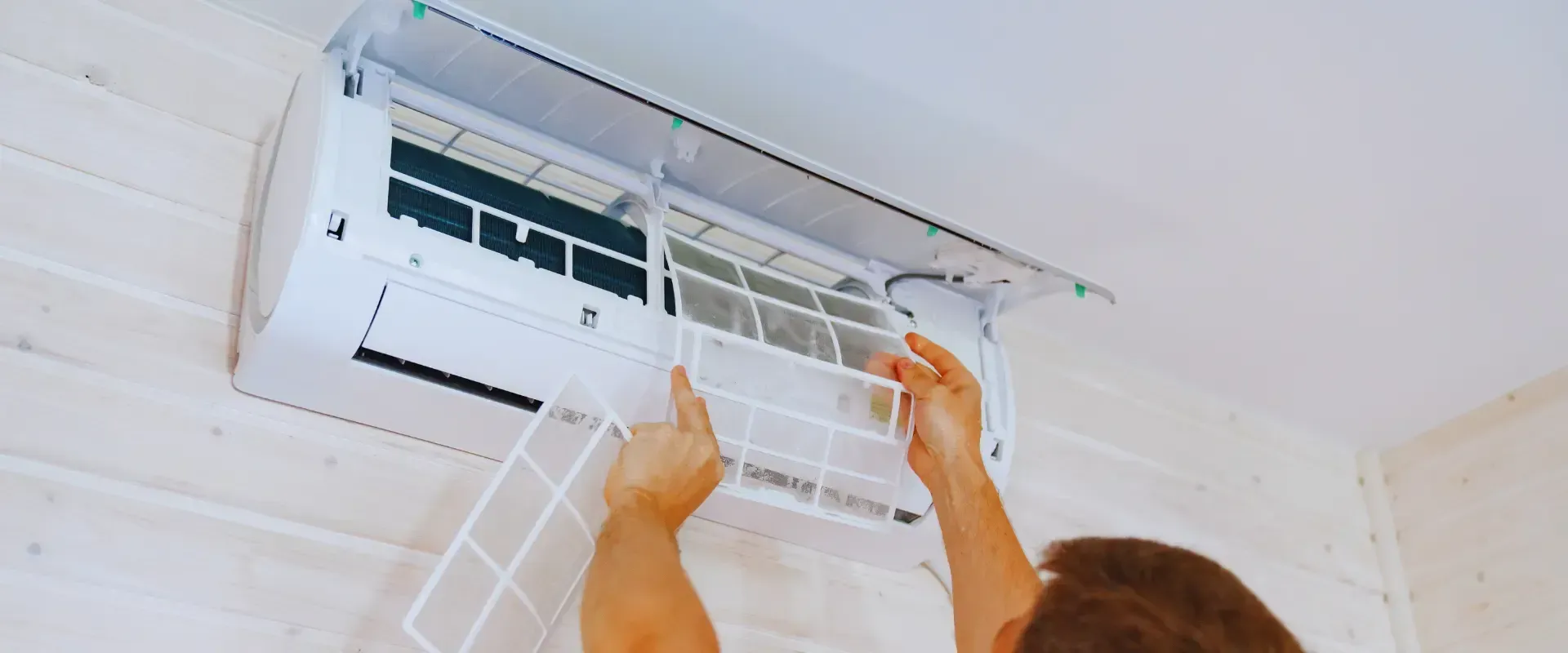 A man is cleaning the filter of an air conditioner.