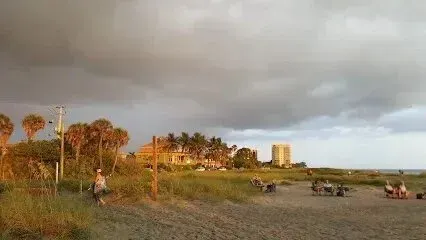 Hvac-Contractor-Bradenton-Beach with dark storm clouds overhead, people near buildings and palm trees.
