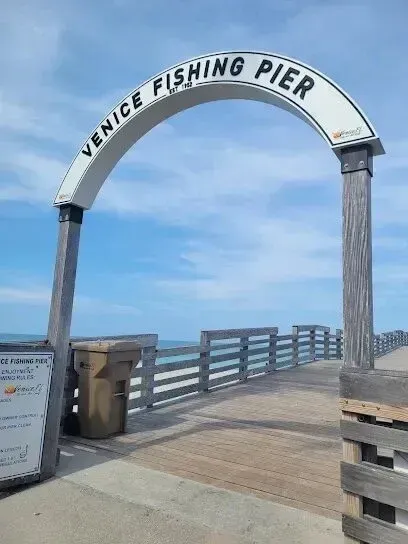 Hvac-Contractor-Bradenton-Venice Fishing Pier entrance archway with sign, wood pier, blue sky, and ocean in background.