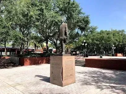 Hvac-Contractor-Bradenton-Statue of a man standing on a pedestal in a park, trees and building in the background.