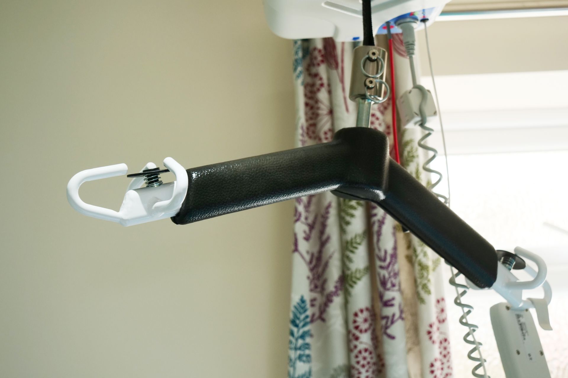 A person lift is hanging from the ceiling in front of a window.