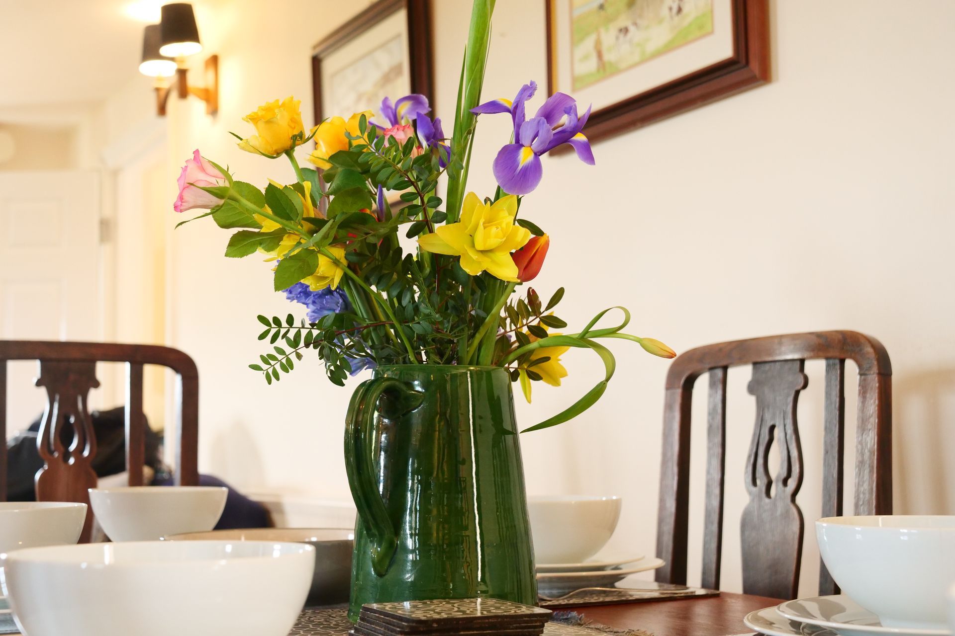 A vase of flowers is on a table in a dining room.