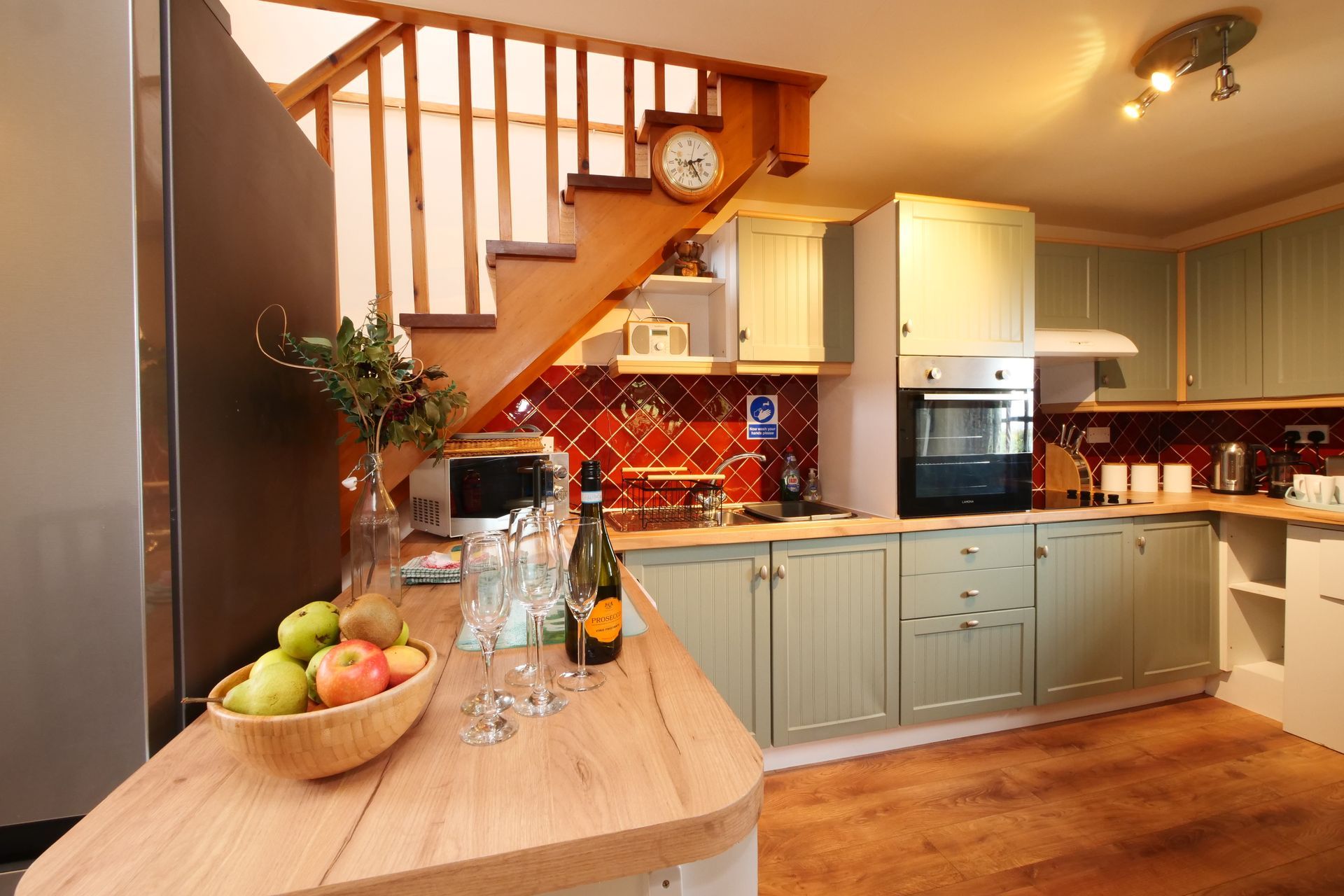 A kitchen with green cabinets and a clock on the wall