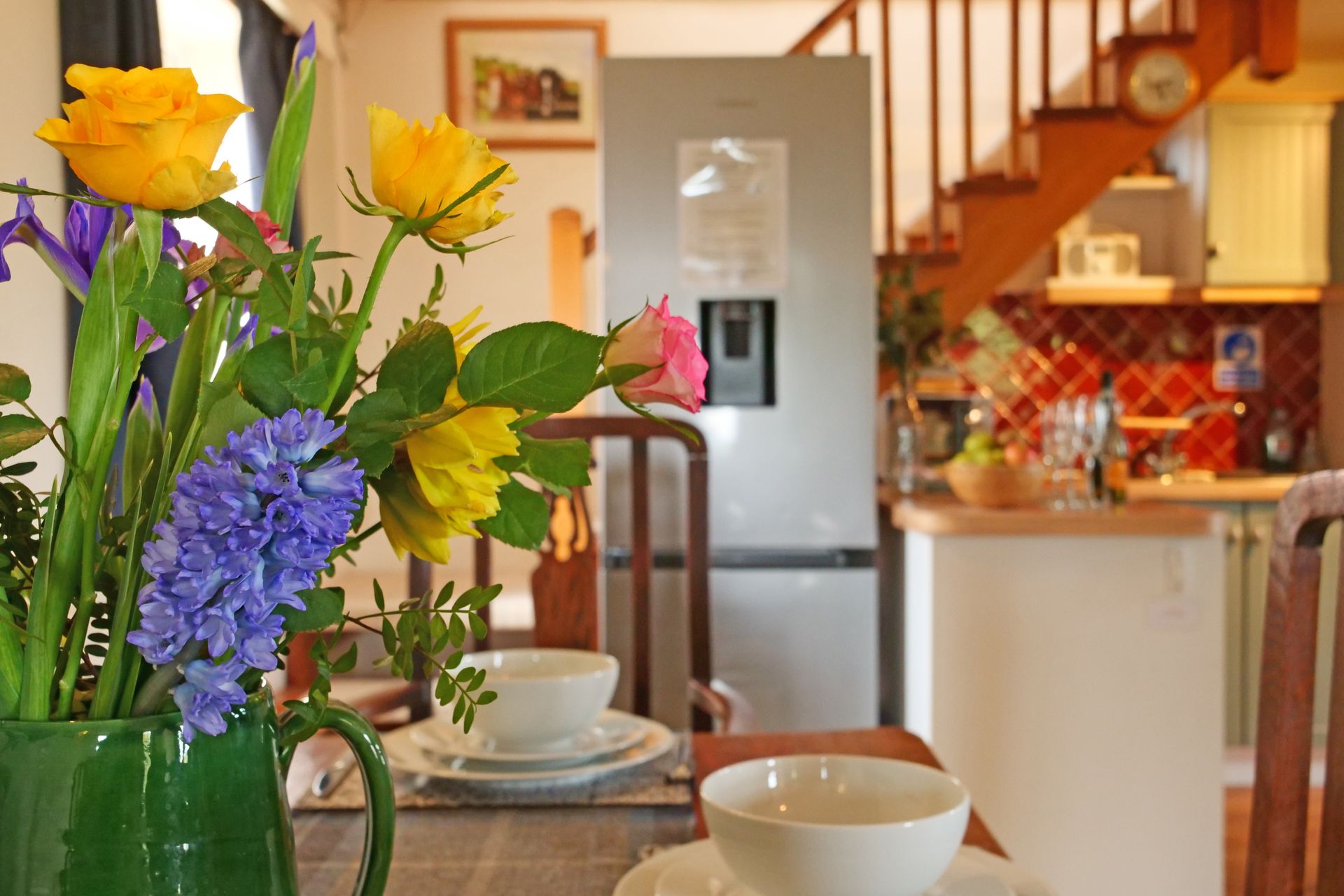 A vase of flowers is on a table in a kitchen.