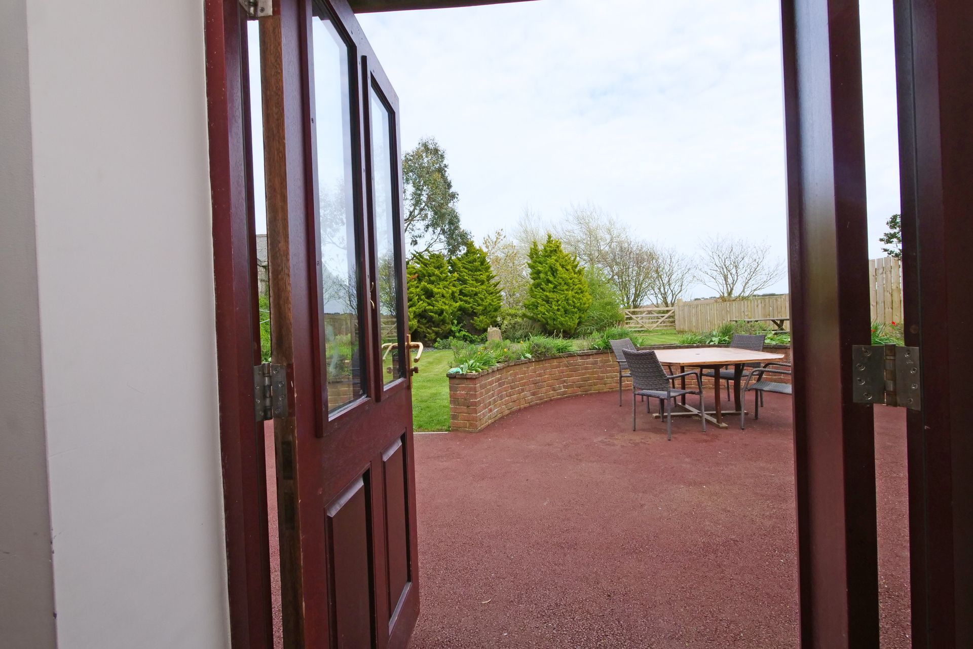 A wooden door is open to a patio with a table and chairs.