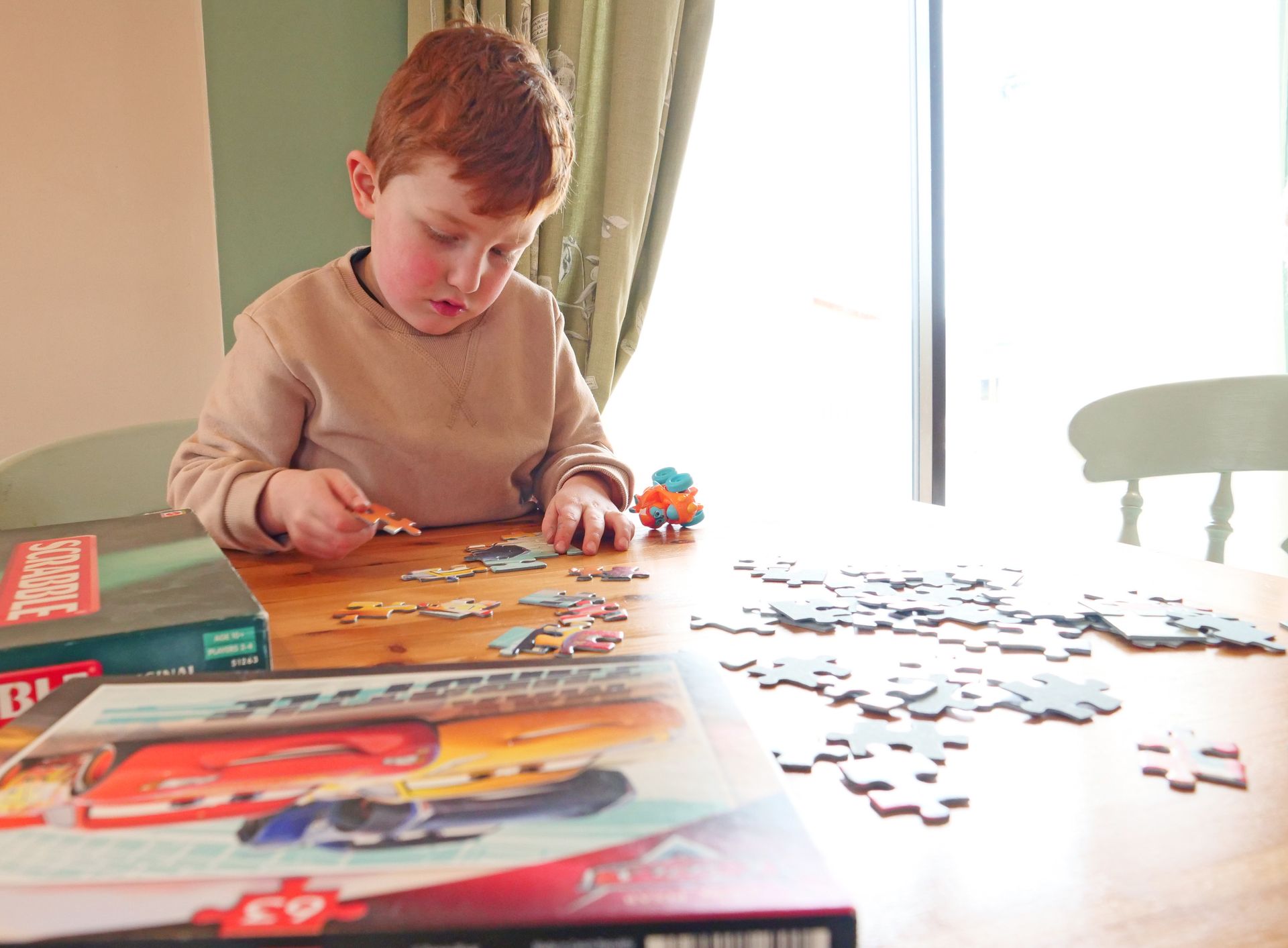 A young boy is sitting at a table playing with a puzzle.
