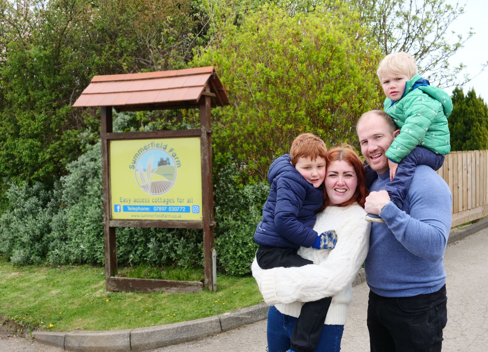 A family is posing for a picture in front of a sign.