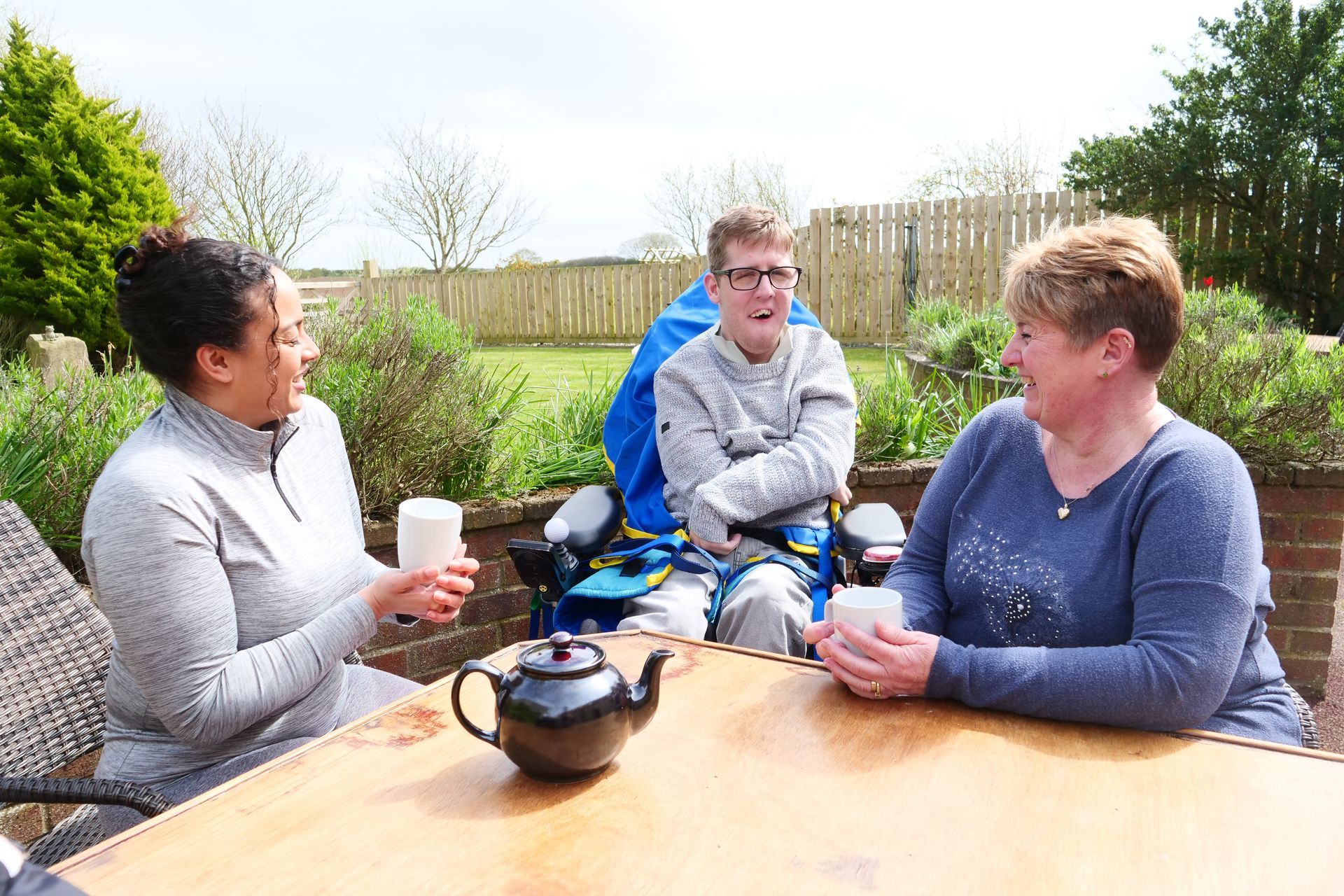 Three women are sitting at a table with a man in a wheelchair.