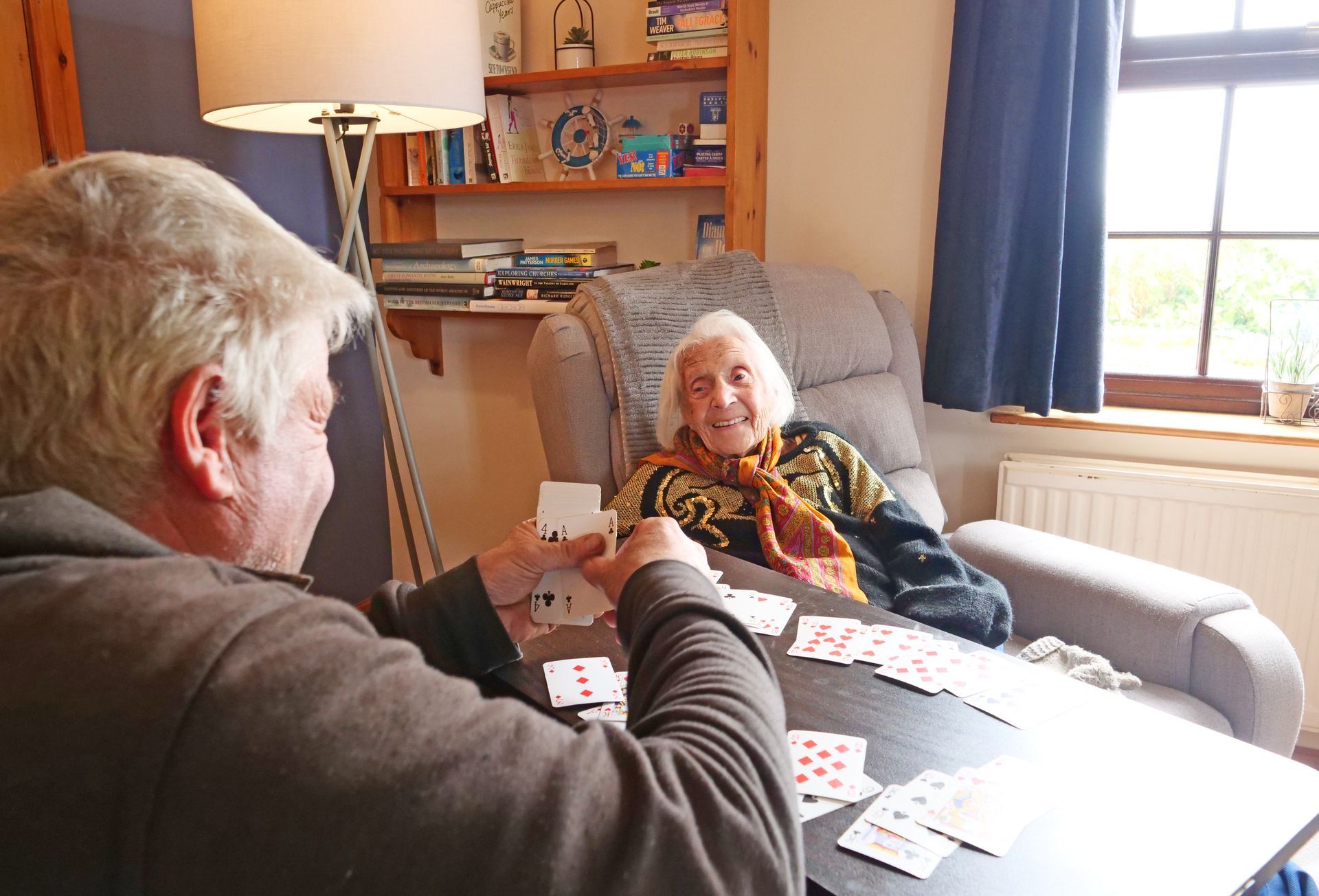 A man and a woman are playing cards together in a living room.