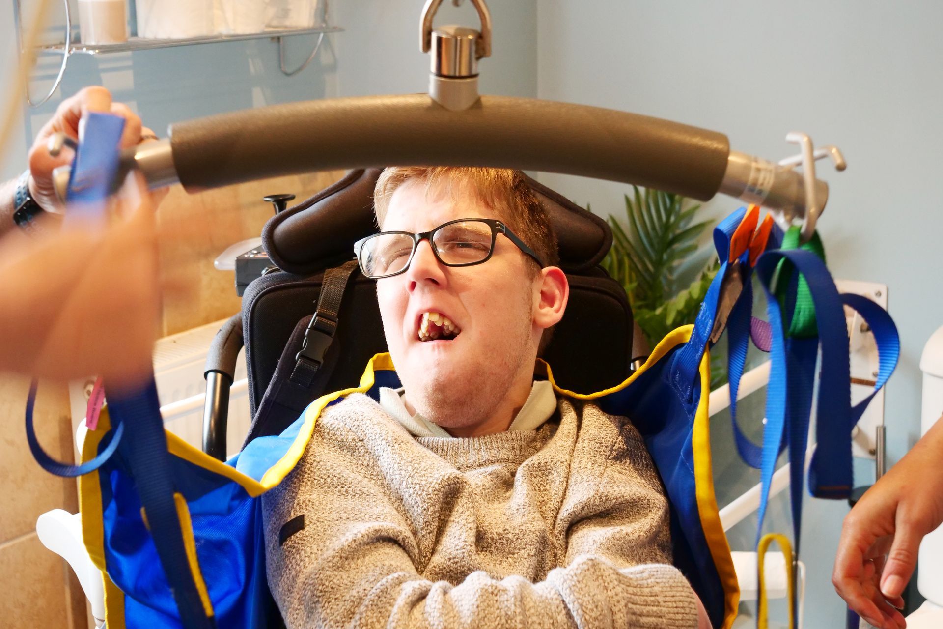 A young man in a wheelchair is being lifted by a person.