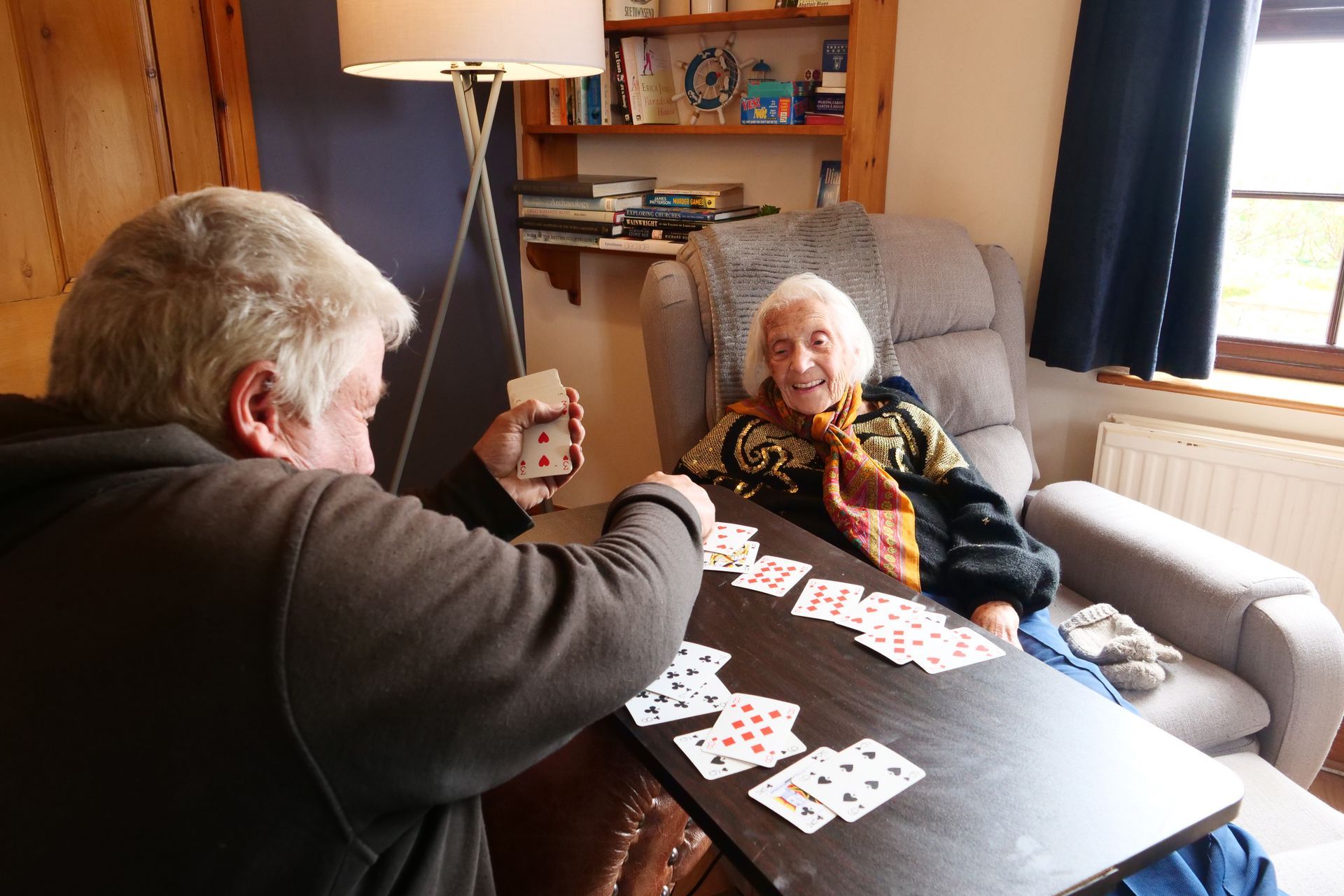A man and a woman are playing cards at a table.