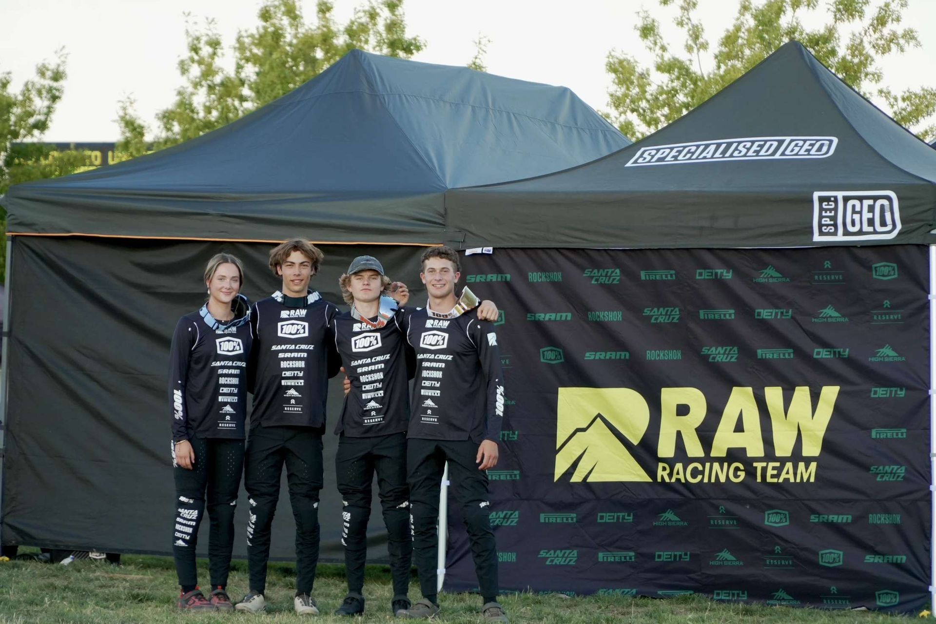 A group of people standing in front of a raw racing team tent