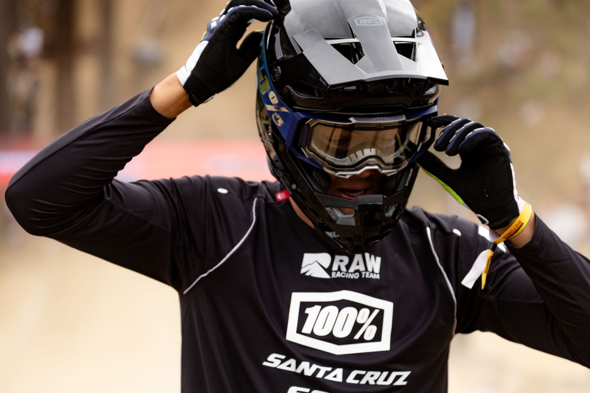A man wearing a helmet and goggles is wearing a shirt that says 100 % santa cruz