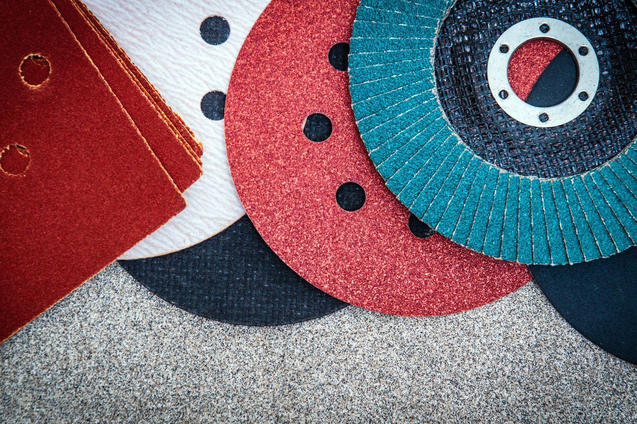 Un montón de discos de lijado de diferentes colores están sobre una mesa.