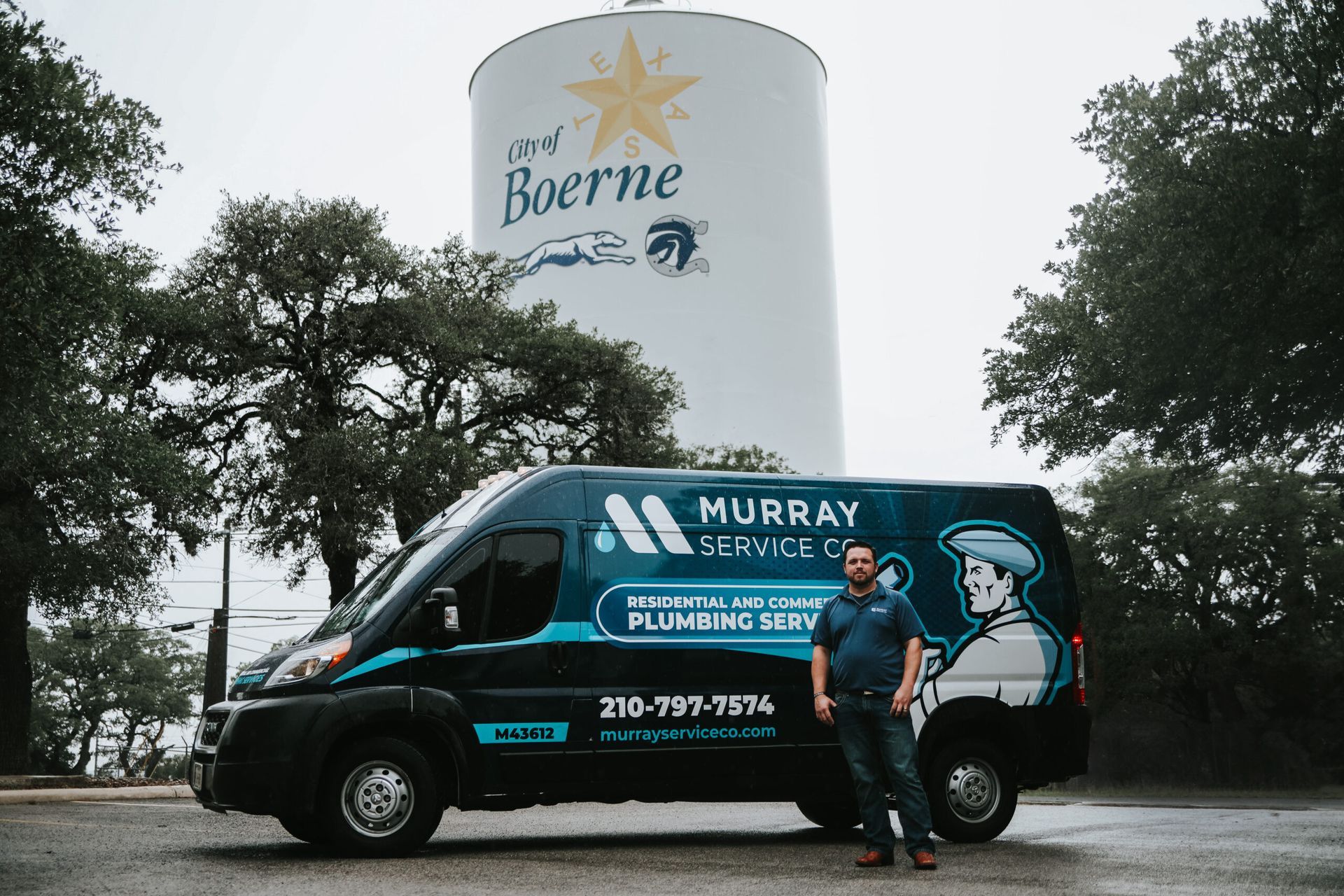 Man stands by his plumbing service van in Boerne, Texas, near the city water tower.