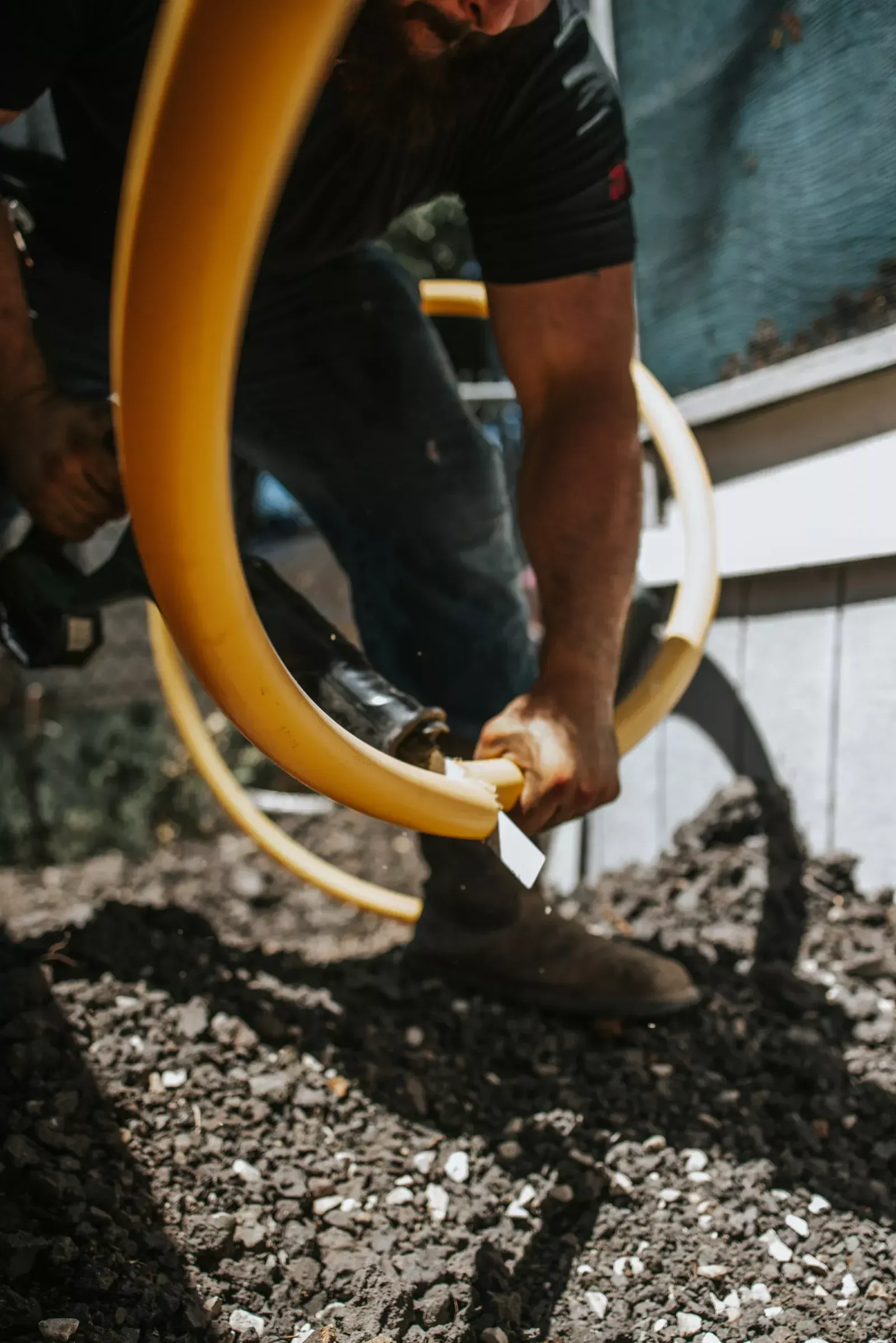 Man installing yellow gas line in dirt.