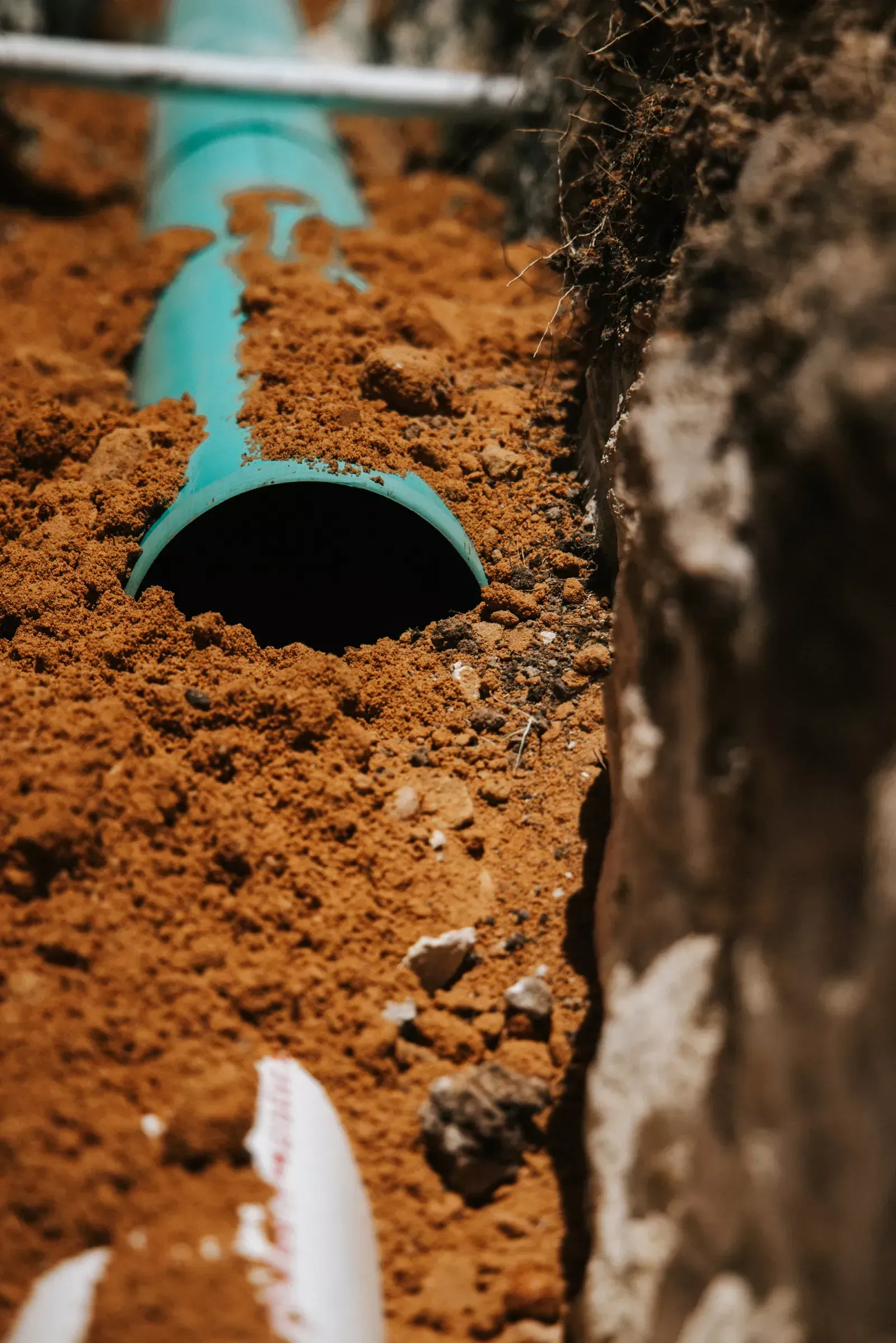Green pipe in a trench with exposed soil, detail shot.