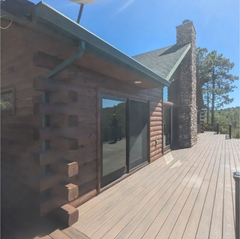 A large log cabin with a large deck in front of it