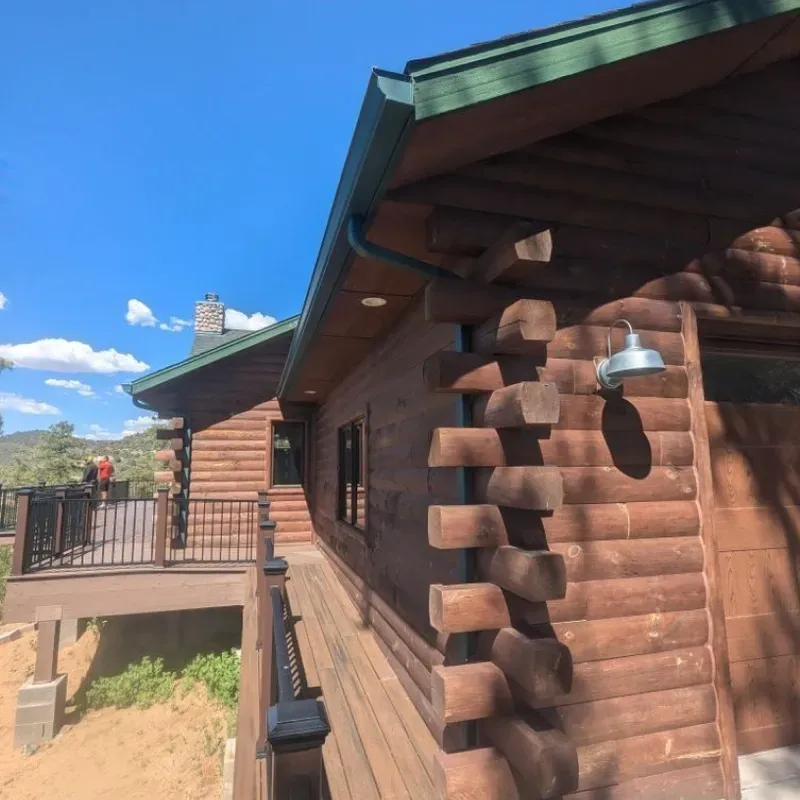 A log cabin with a green roof and a balcony