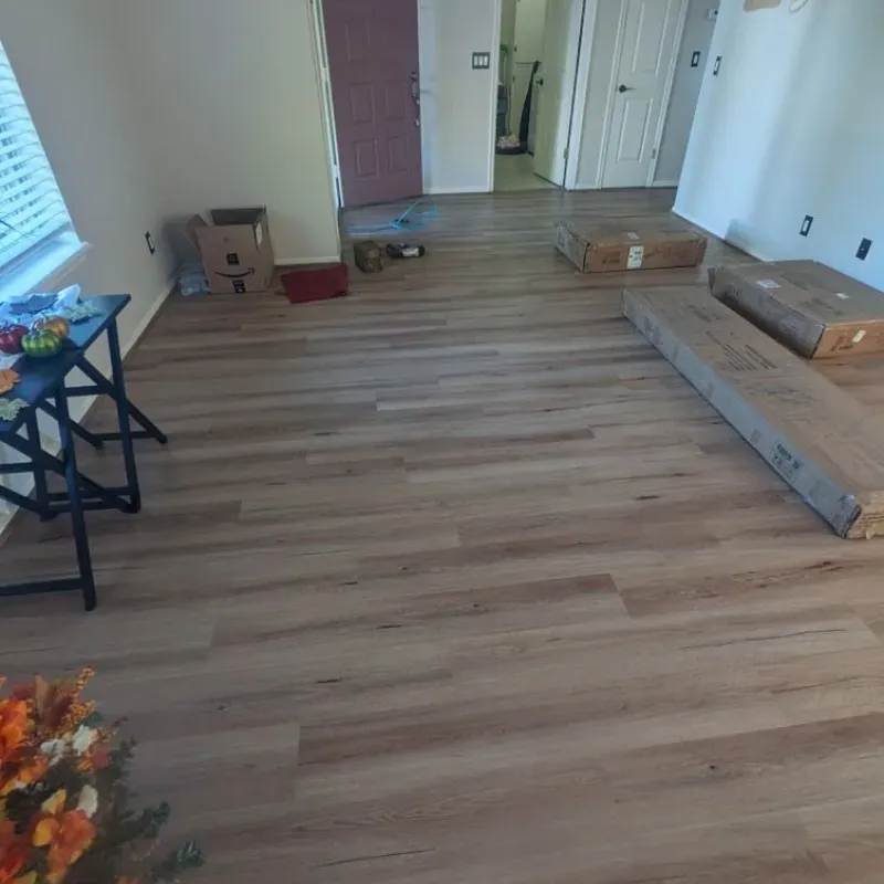 A living room with hardwood floors and boxes on the floor.