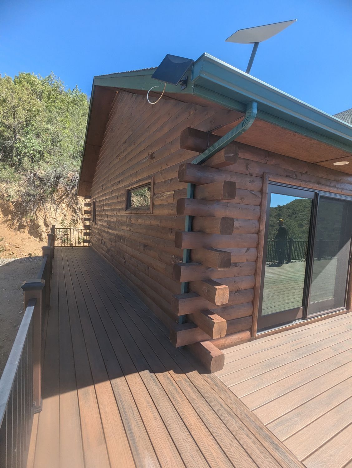 A log cabin with a deck and a satellite dish on the roof.