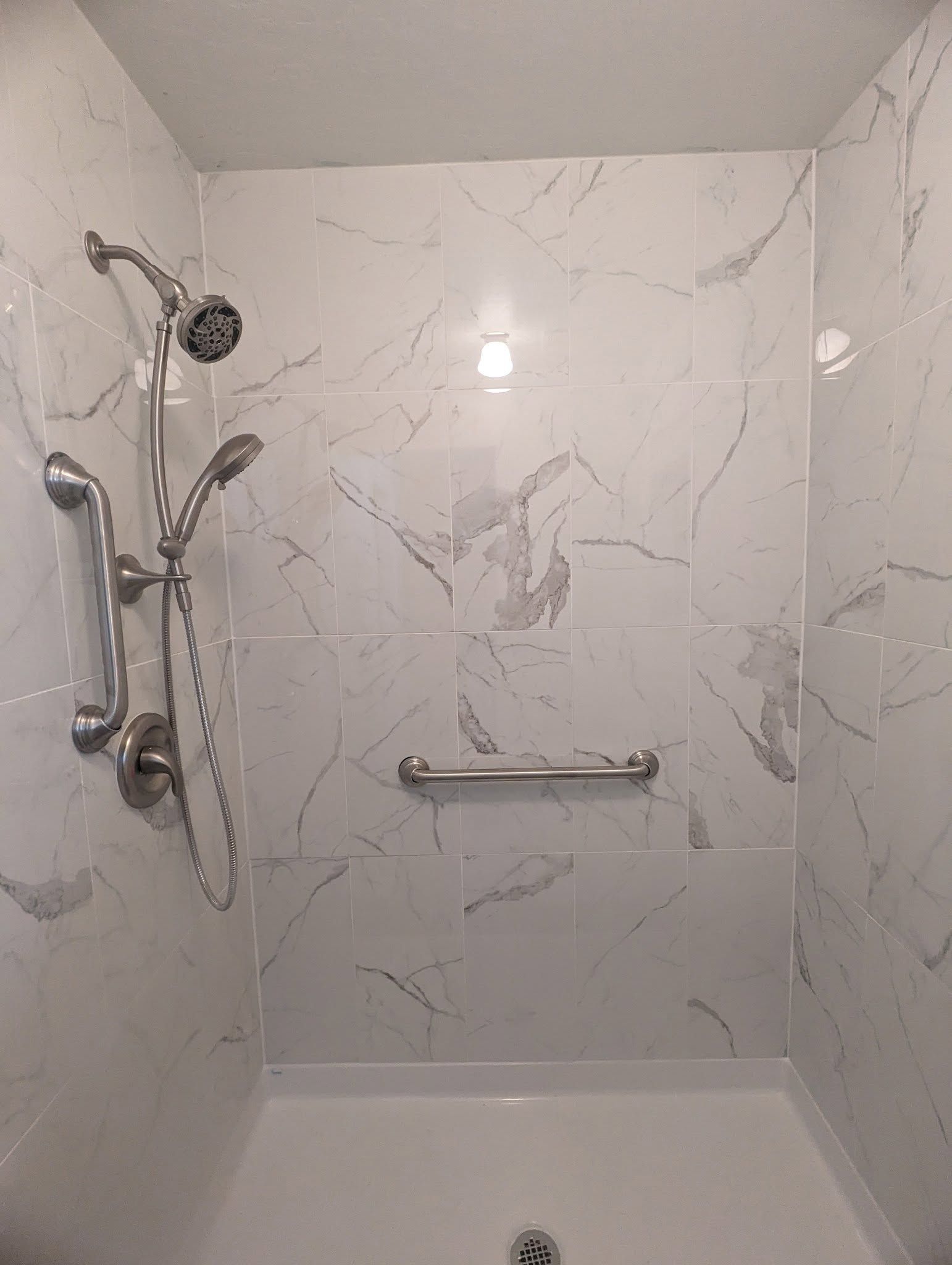 A shower with a hand rail and a shower head.