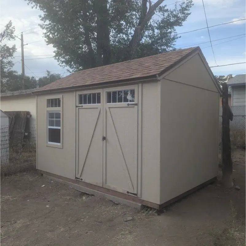 A white shed with a brown roof and two windows