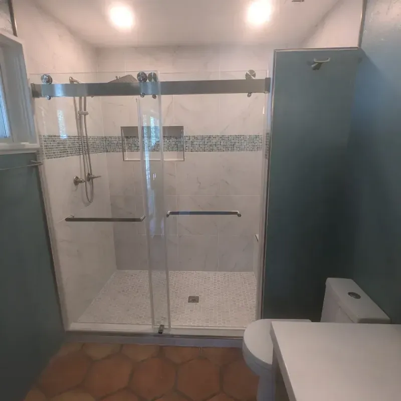 A bathroom with a sliding glass shower door and a toilet.