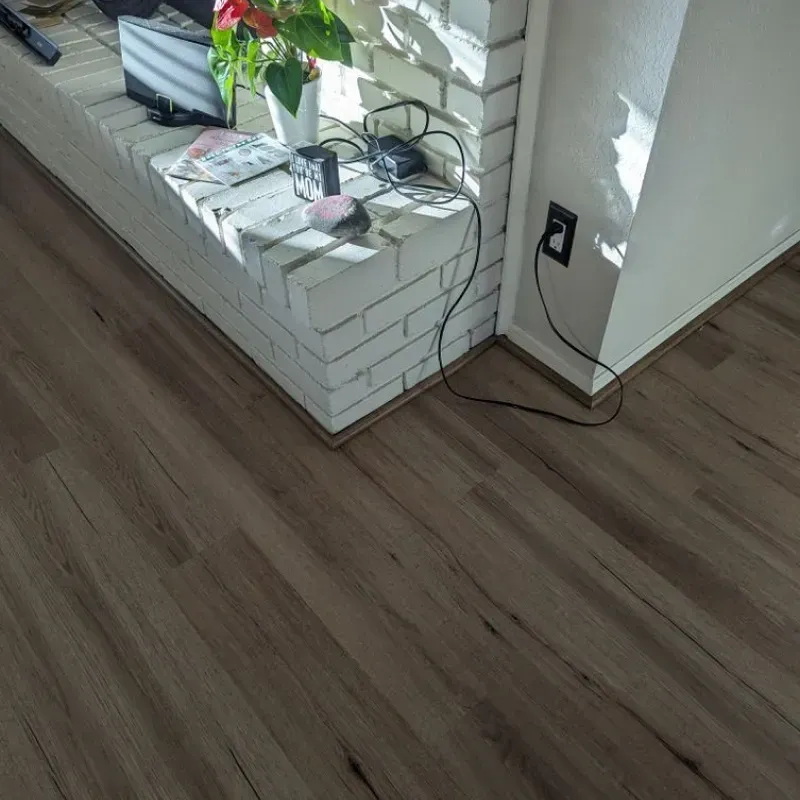 A living room with a wooden floor and a brick wall.