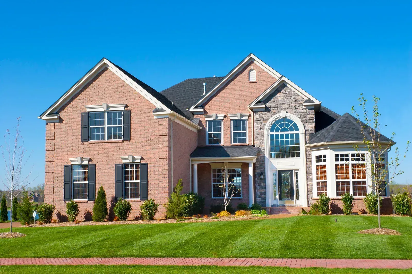A large brick house with a lush green lawn in front of it