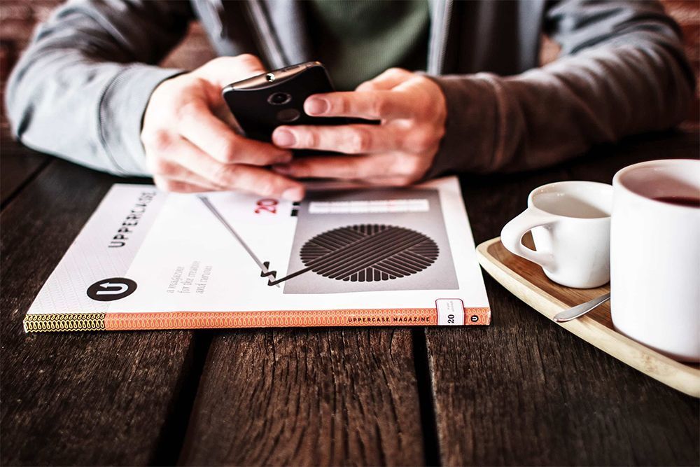 A man is sitting at a table using a cell phone