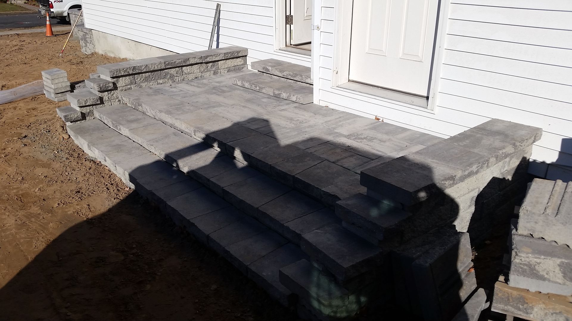 Construction workers laying gray paving stones on a gravel base.