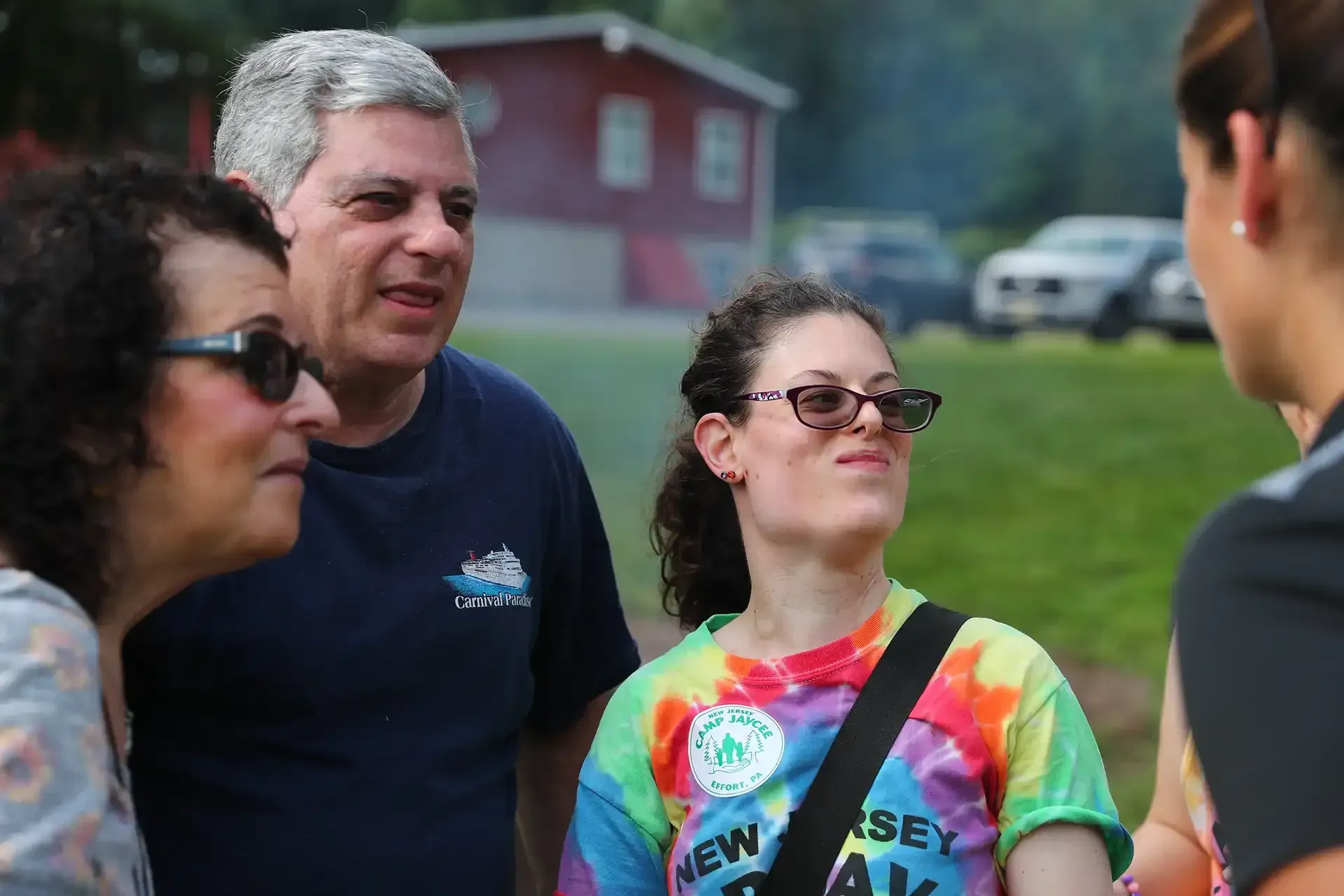 Group of people outdoors, some wearing sunglasses, talking in front of a building.