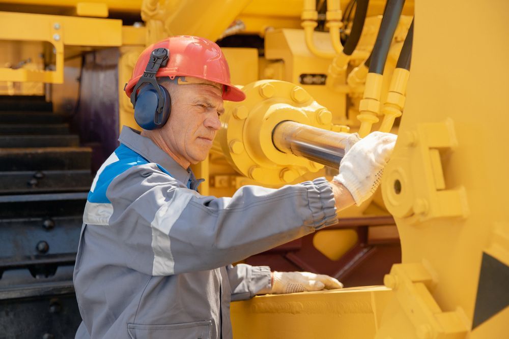 Worker in Red Hard Hat Inspecting Yellow Industrial Machinery — Harris Engineering Services CQ In Gracemere, QLD