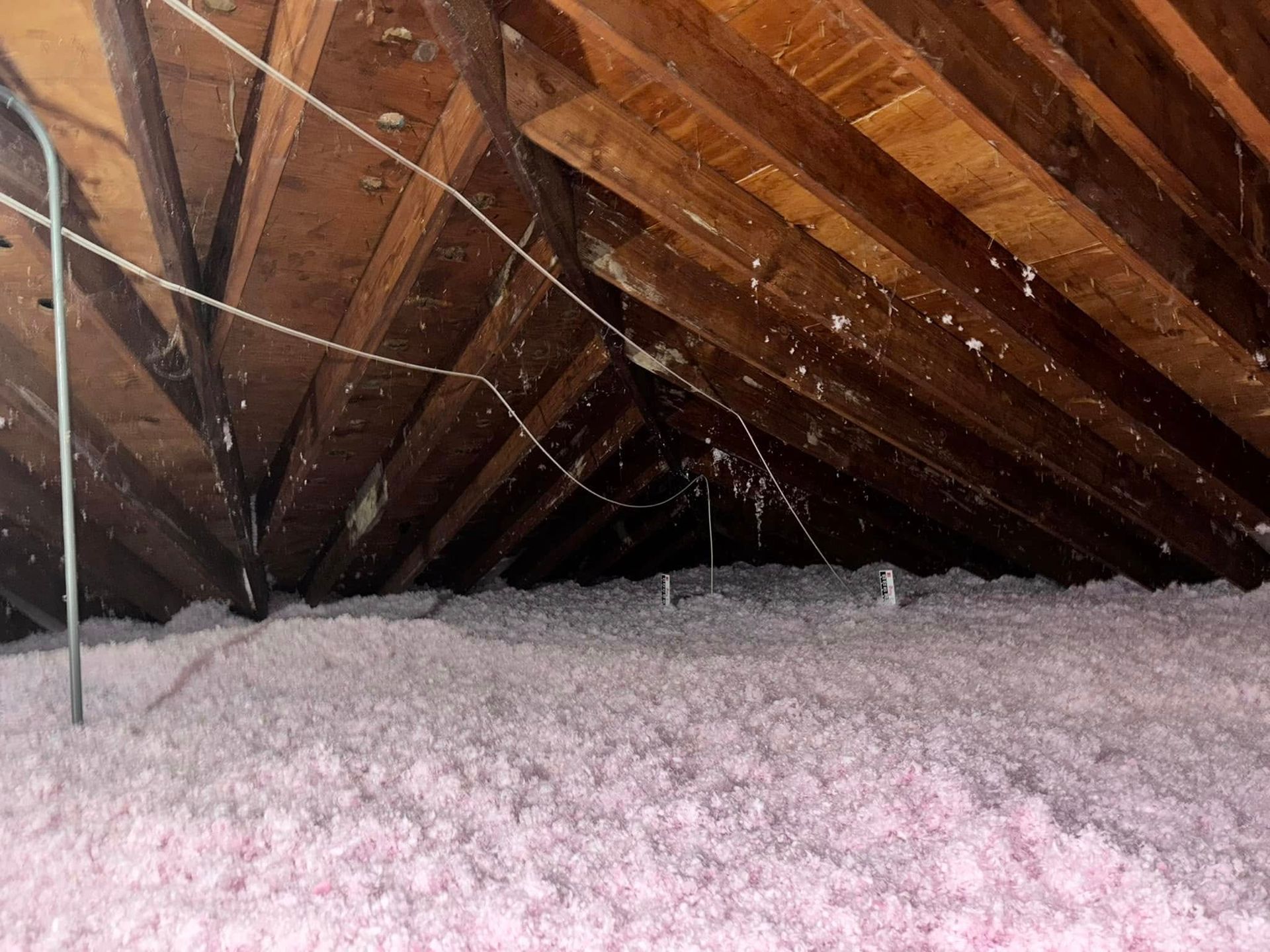 There is a lot of pink insulation in the attic of a house.