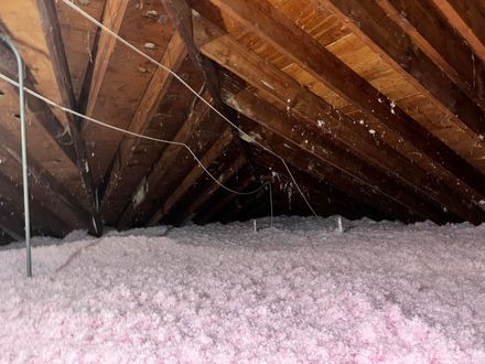 There is a lot of pink insulation in the attic of a house.
