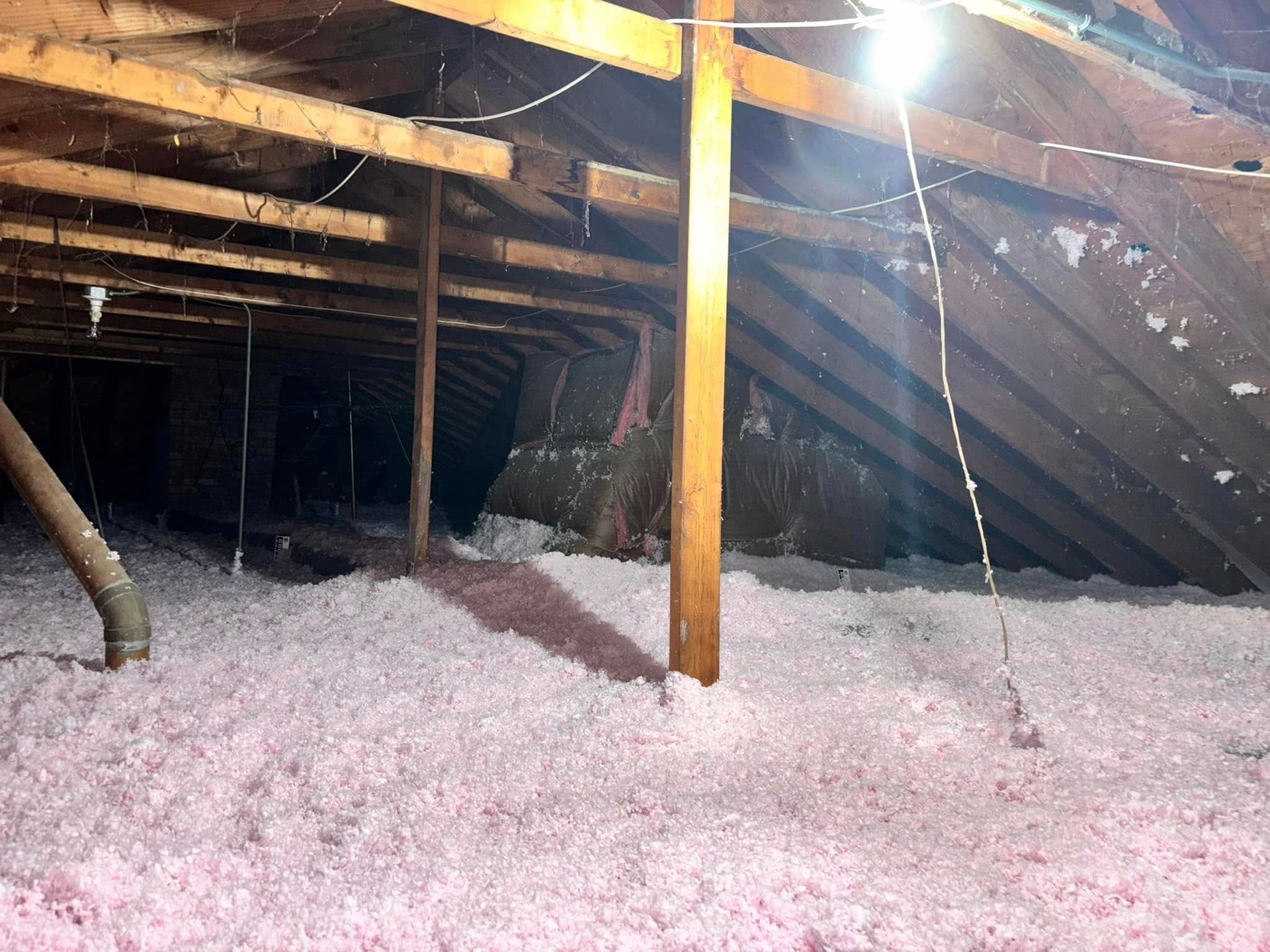 There is a lot of pink insulation in the attic of a house.